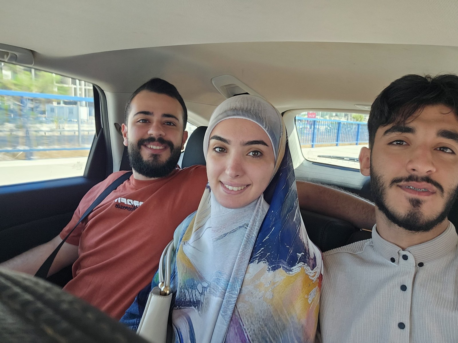 Alaa with two loved ones smiling in a car
