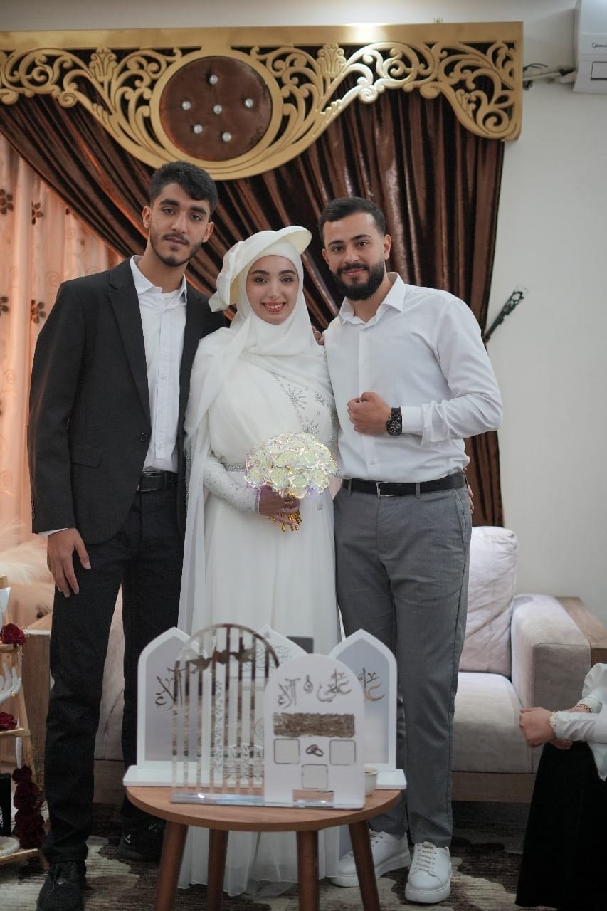 Alaa dressed in white with two loved ones at a celebration